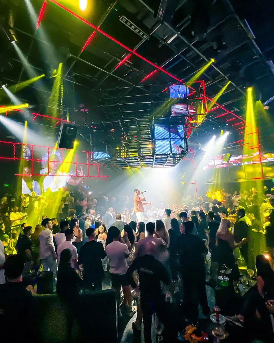 Live performance on stage with crowd dancing under yellow spotlights at Ora Club Dubai Night club